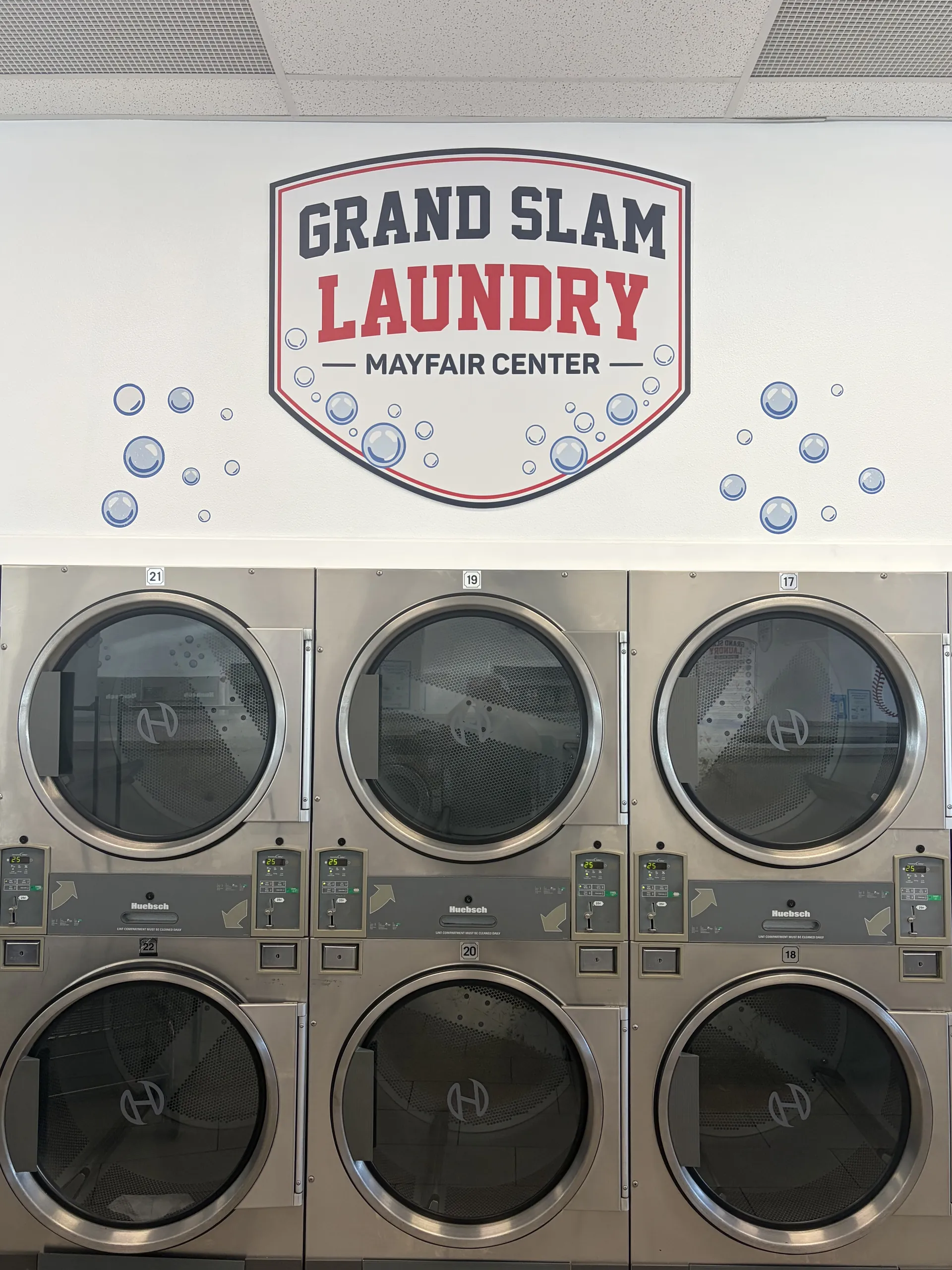 Grand Slam Laundry logo above a stack of dryers